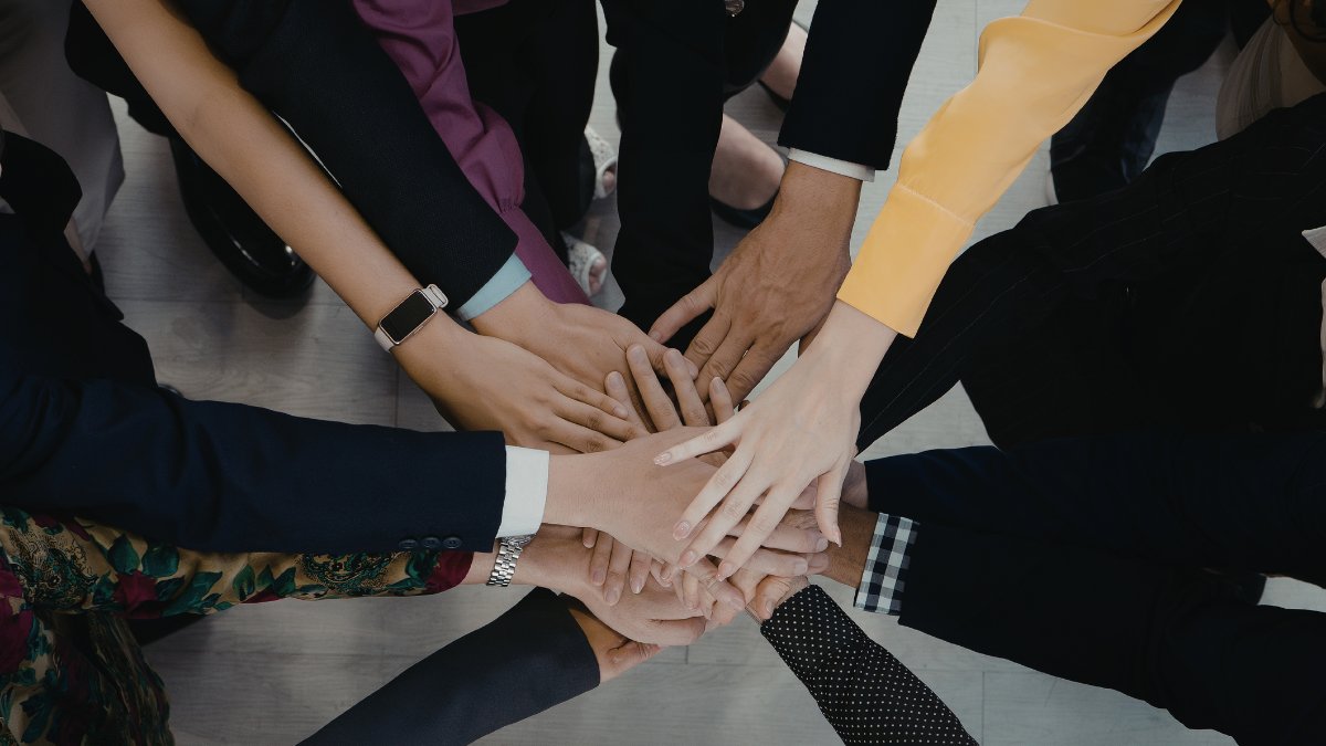 A group of people putting their hands together in a circle to show teamwork.